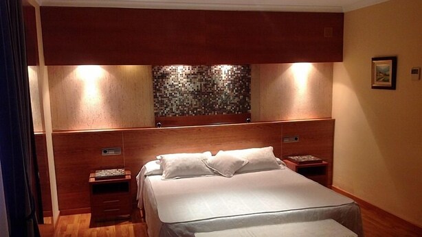 Ein ordentlich eingerichtetes Schlafzimmer mit einem großen Bett, einem Holz-Kopfteil und einer Wand mit Mosaik.