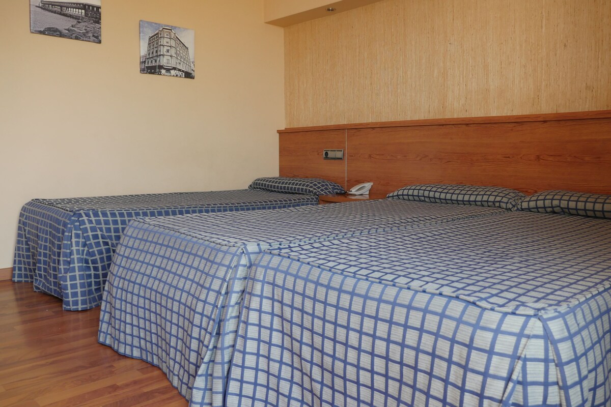 Una habitación con dos camas, cabecero y techo de madera.