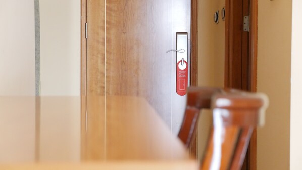 A hotel room with a wooden door, a red sign with a symbol and text, and a chair in the foreground. - Rusadir (Melilla)