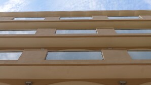 Ein mehrgeschossiges Gebäude mit einer beigen Fassade und rechteckigen Fenstern.