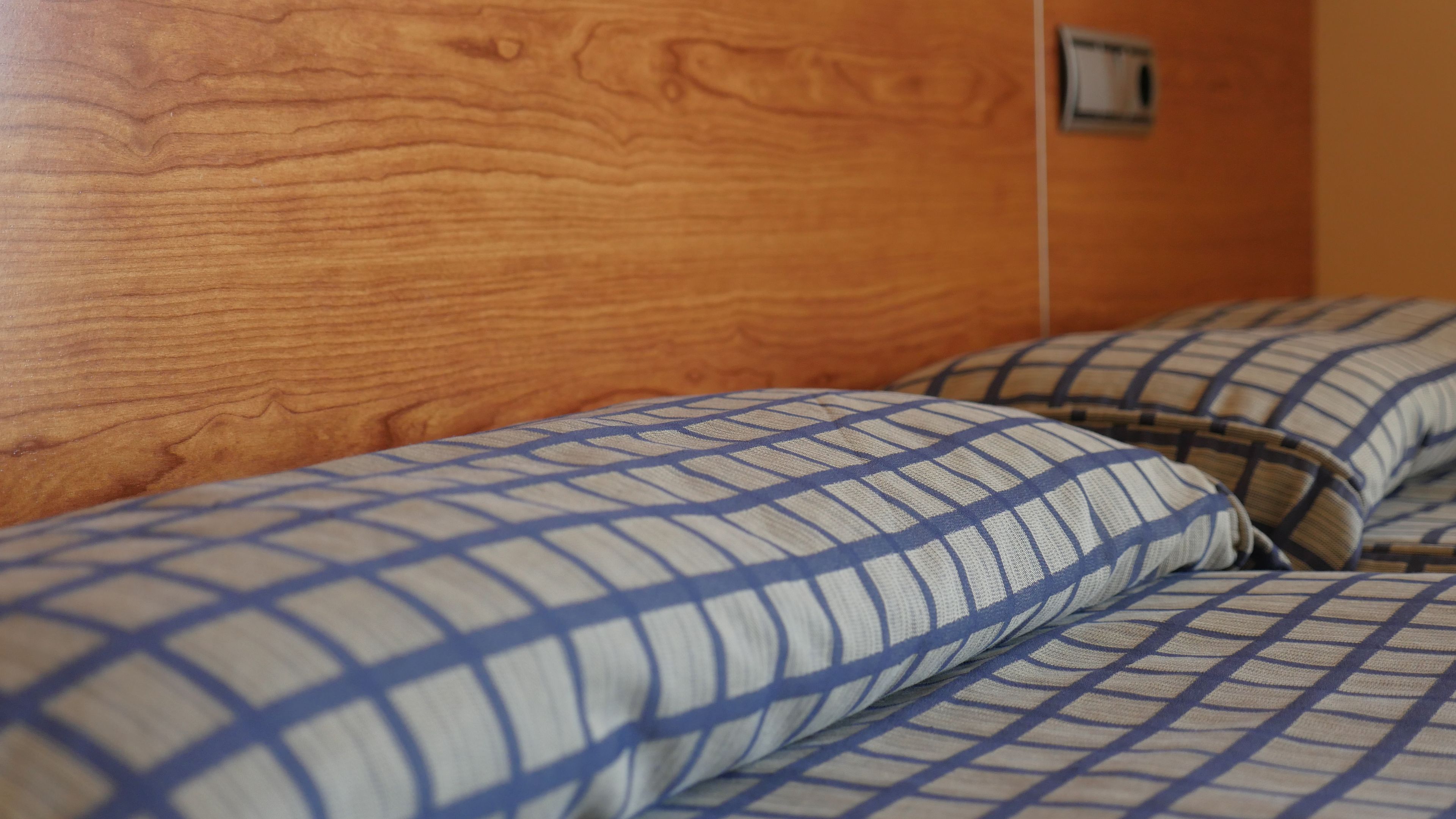 Una cama con un cojín a cuadros y un cabecero de madera.