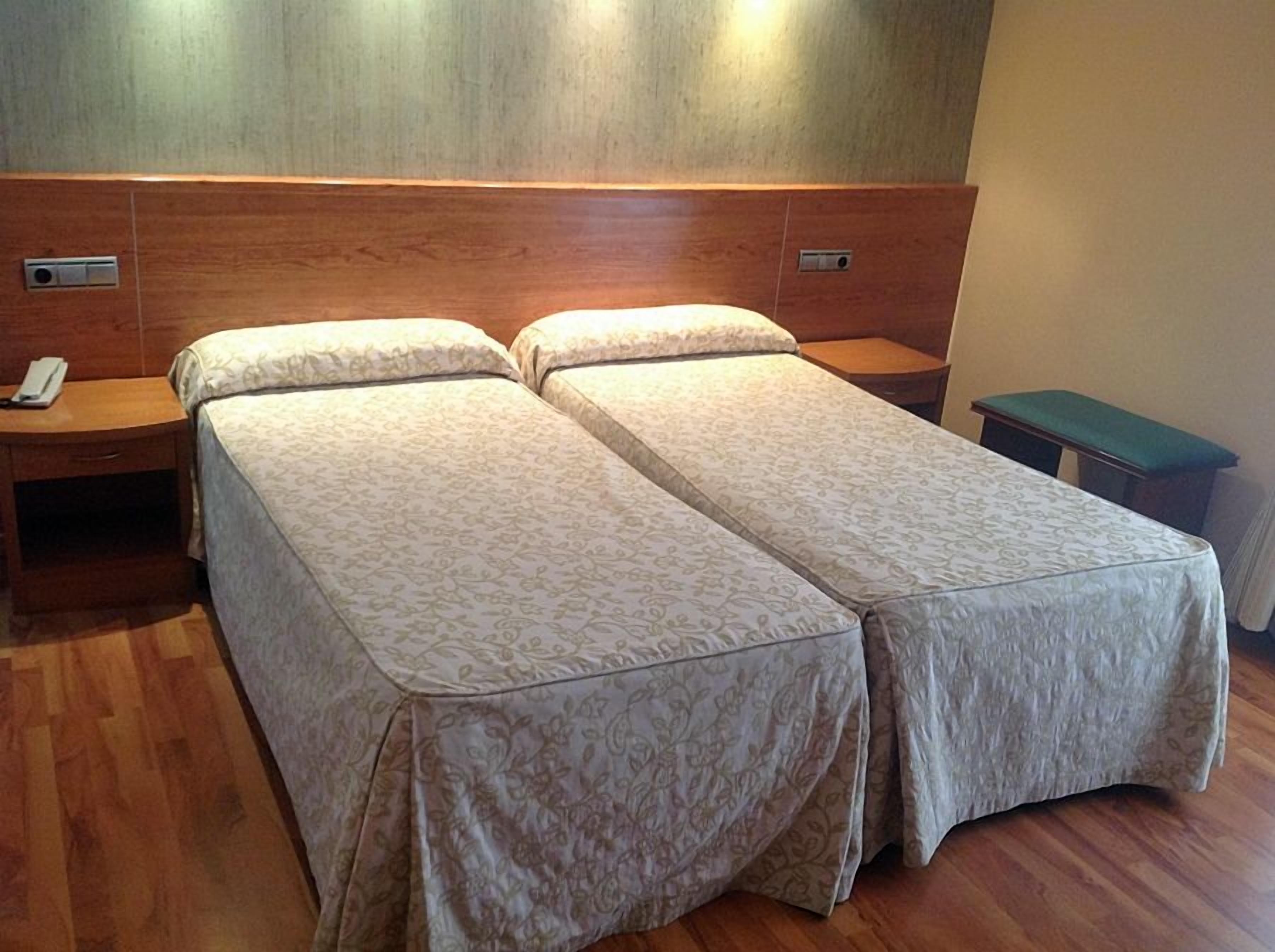 A double bed with a wooden headboard and two bedside tables, one with a phone.