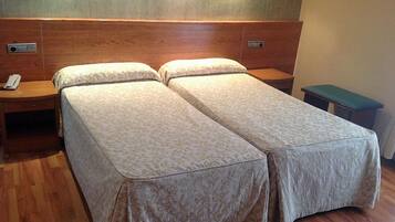 A double bed with a wooden headboard and two bedside tables, one with a phone.