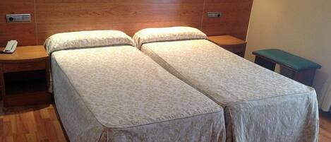 Una cama doble con cabecera de madera y dos mesitas de noche, una de ellas con un teléfono.