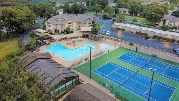 Ein Wohngebiet mit Schwimmbad, Tennisplätzen und einem großen Haus mit Auffahrt.