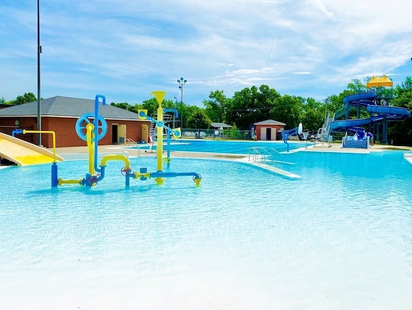 Ein Schwimmbad mit Wasserrutschen und einem kleinen Gebäude im Hintergrund.