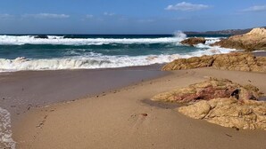 Una playa con aguas cristalinas, formaciones rocosas y una orilla arenosa.
