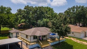 A single-story house with a covered patio, a flag, and a lawn. - Spotless 2-Bedroom Cottage, Highly Recommended (Mabank)