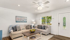 A living room with a beige sofa, a coffee table, and a ceiling fan. - Spotless 2-Bedroom Cottage, Highly Recommended (Mabank)