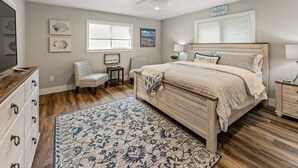 A bedroom with a wooden bed, a ceiling fan, a large window, and a decorative rug. - Spotless 2-Bedroom Cottage, Highly Recommended (Mabank)