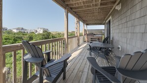 Une terrasse en bois, agrémentée de mobilier d’extérieur et d’une pergola, avec une vue sur les maisons au loin.