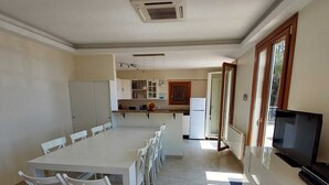 A spacious kitchen with a dining area, a built-in TV, and a large window.