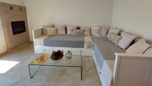 A living room with a sectional sofa, a glass coffee table, and a fireplace.