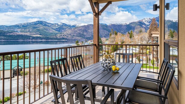 Een balkon met een tafel en stoelen, met uitzicht op een meer en bergen.