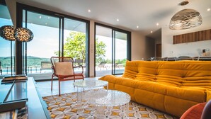 Un salon moderne avec un canapé jaune, une table basse en verre et un tapis à motifs.