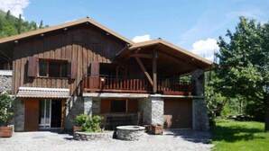 Un bâtiment en bois à deux étages, doté d’un balcon, de fondations en pierre et d’une allée gravillonnée.