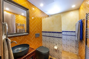 A bathroom with a large mirror, a black sink, a towel rack, and patterned tiles. - CASA FELIZ TWO BEDROOM A406 (Germasogeia)
