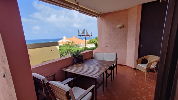 A balcony with a table and chairs, a view of the sea, and a door. - Spacious apartment in seafront condo (Portu Maga)