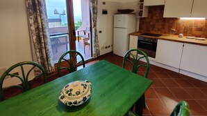A compact kitchen with a dining area, a refrigerator, and a view through the sliding glass door. - Spacious apartment in seafront condo (Portu Maga)