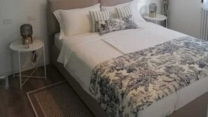 A bedroom with a large bed, a bedside table, a lamp, and a wall-mounted artwork. - Mi-Re-La House in the vicinity of historic Villa Manin - Codroipo (CODROIPO)