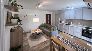 A compact living space with a sofa, a dining table, a kitchen area, and a pendant light. - Mi-Re-La House in the vicinity of historic Villa Manin - Codroipo (CODROIPO)