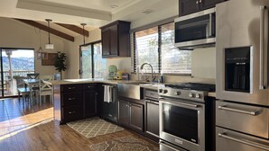 A modern kitchen with stainless steel appliances, dark cabinetry, and a large window providing natural light. - Lake Naci Rendezvous with Lake Views (Bradley)