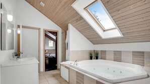 A modern bathroom with a freestanding bathtub, skylight, and a visible doorway leading to another room. - Beautiful home in Væggerløse with WiFi (Væggerløse)