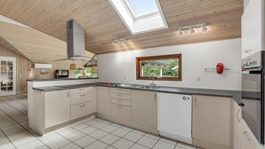 A modern kitchen with wooden ceiling beams, a skylight, and a large window. - Beautiful home in Væggerløse with WiFi (Væggerløse)