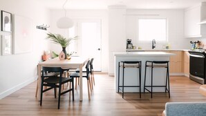 Une cuisine moderne dotée d’un îlot central, de tabourets de bar et d’un coin repas avec des chaises.