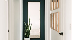 Un couloir avec un plafond sombre, des murs blancs et une grande fenêtre au fond.