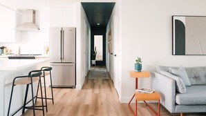 Une cuisine moderne avec des armoires blanches, des appareils en acier inoxydable et un plancher en bois.