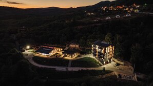 Un hotel moderno con diversi edifici, un'area parcheggio e un paesaggio collinare circostante.