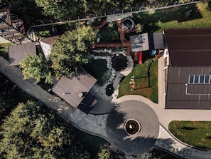 An aerial view of a park with a circular paved area, wooden decks, and a building with a metal roof.