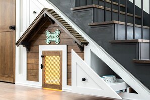 A staircase with a wooden handrail and a doghouse with a bone-shaped sign. - 7-Bdrm Lake View Firepit & More Pets ok (Kingston)