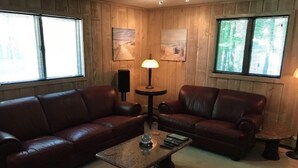 A room with two leather sofas, a coffee table, a lamp, and artwork on the walls. - Luxury Apartment in Private Home. Private Entrance. Close to Horse Show, Beaches (Williamsburg)