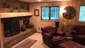 A cozy living room with a fireplace, leather chairs, and a rug. - Luxury Apartment in Private Home. Private Entrance. Close to Horse Show, Beaches (Williamsburg)