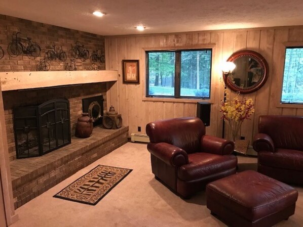 A cozy living room with a fireplace, leather chairs, and a rug.