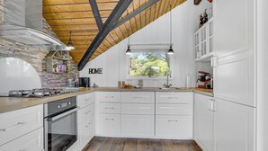 A modern kitchen with white cabinets, a stone backsplash, a gas stove, and a wooden ceiling. - Nice home in Løkken with kitchen (Løkken)