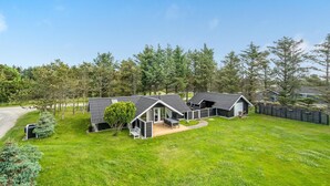 A modern house with a large lawn, a covered patio, and a fenced yard. - Nice home in Løkken with kitchen (Løkken)