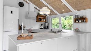 A modern kitchen with white cabinetry, a wooden ceiling, and a large window offering a view of greenery. - Lovely home in Odder with kitchen (Odder)