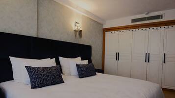 A bedroom with a large bed, a headboard, a wardrobe, and a wall-mounted light fixture.