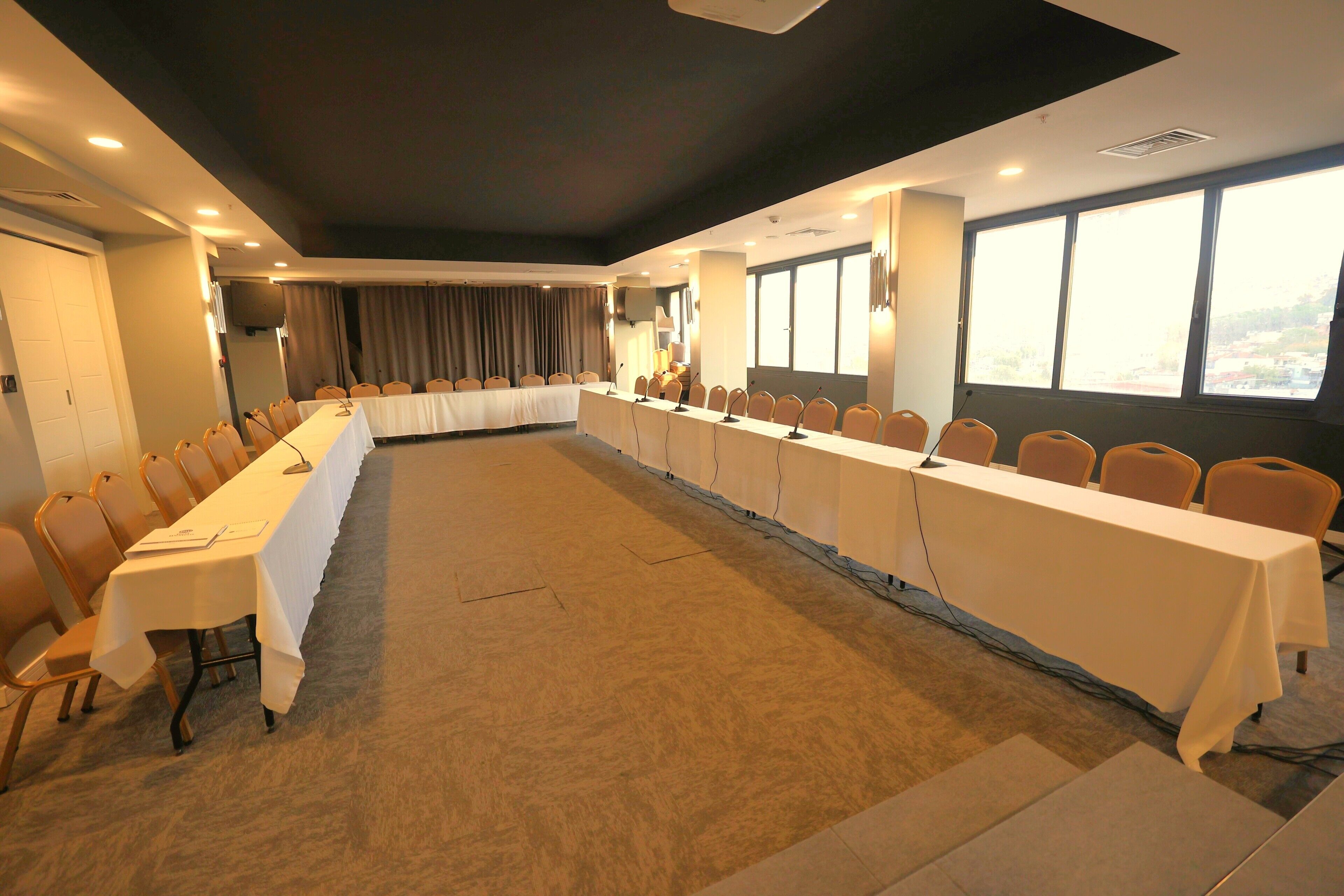 A conference room with a long table, chairs, and a large window providing a view.