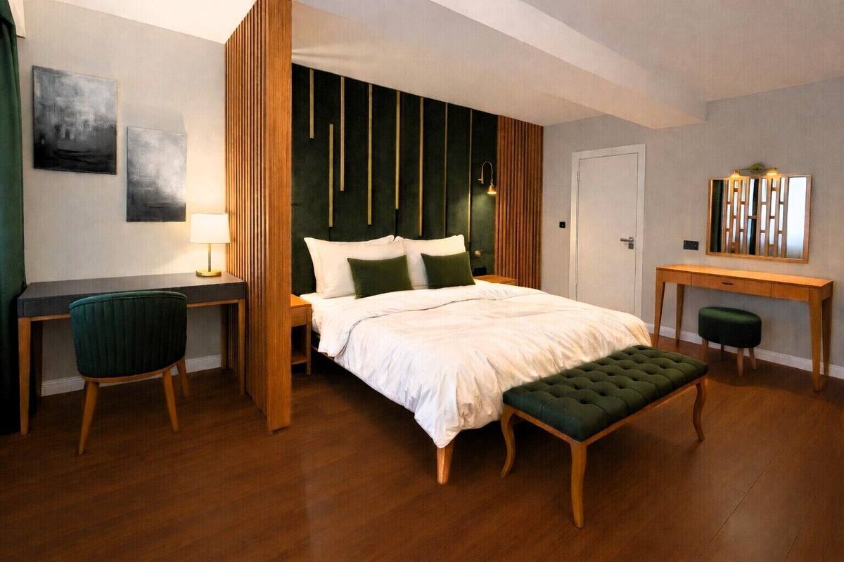 A modern bedroom with a large bed, a desk, and a chair.