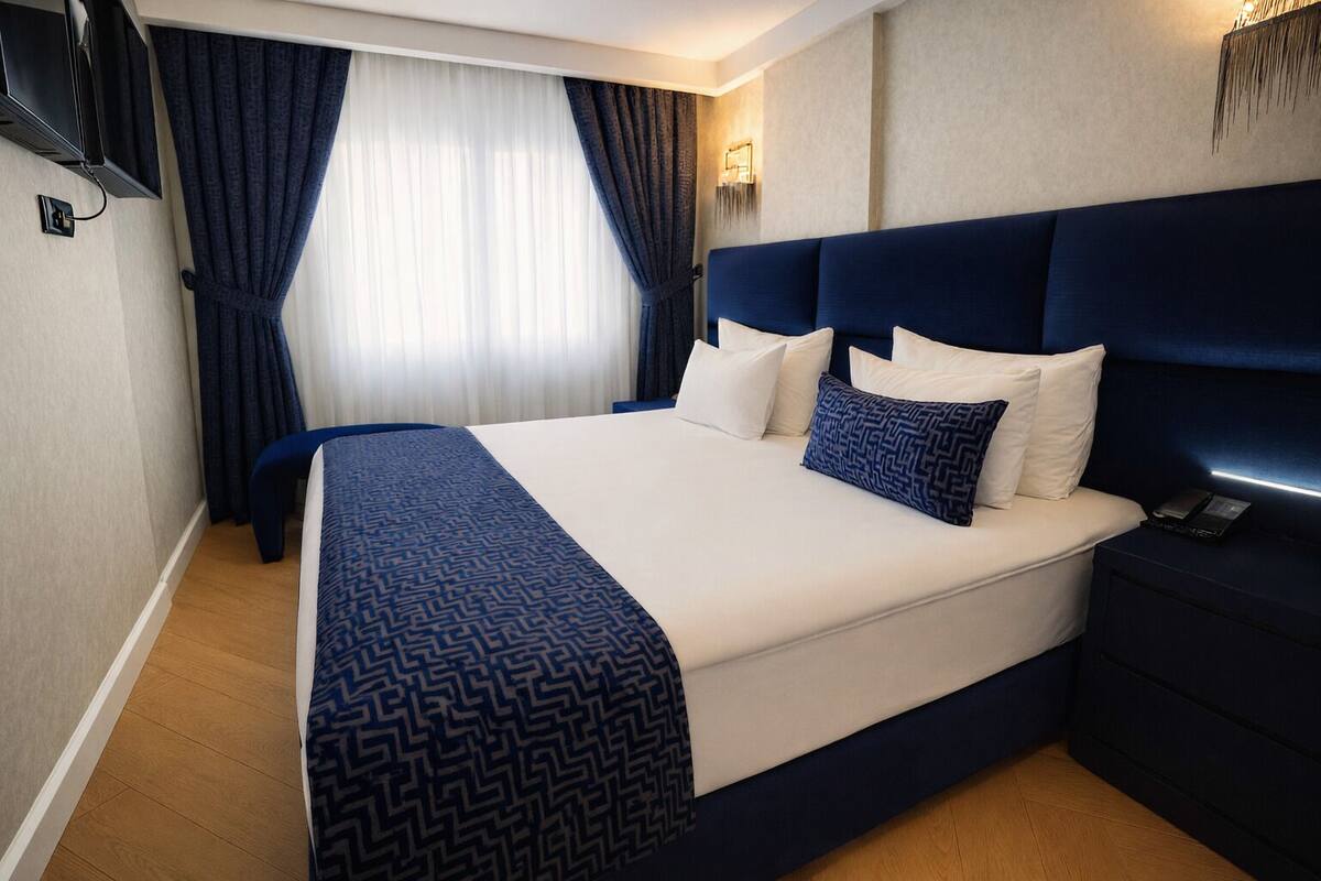 A hotel room with a large bed, a dark headboard, and a bedside table with a phone.