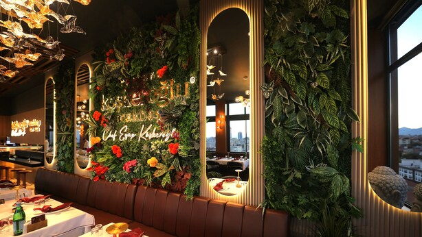 Un restaurant doté d'un mur végétal, d'une enseigne au néon et offrant une vue sur la ville.