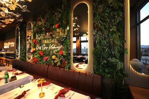A restaurant with a green wall, a neon sign, and a view of the city. - Best Western Izmir Hotel (Izmir)