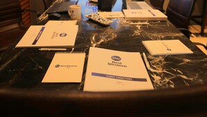 Une salle de conférence avec une longue table, des ordinateurs portables, des cahiers et un écran de projection affichant le logo « BW Best Western ».