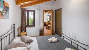 Ein Schlafzimmer mit Bett, Fenster, Tür und Blick auf einen Essbereich.
