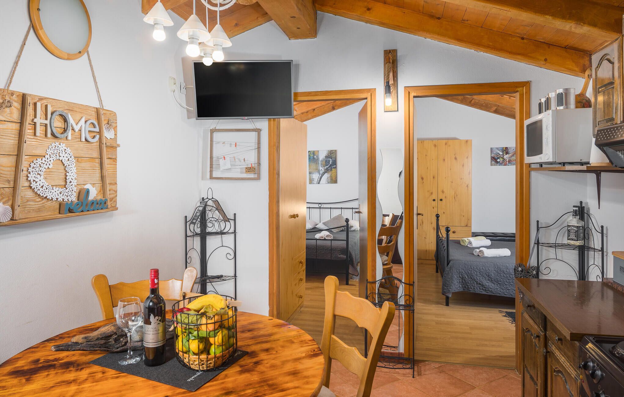 Una habitación acogedora con una mesa de comedor de madera, un televisor montado en la pared y una cama con colcha azul.