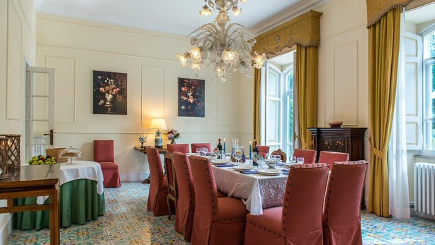 Comedor con piso floral, una araña y sillas tapizadas en rojo.